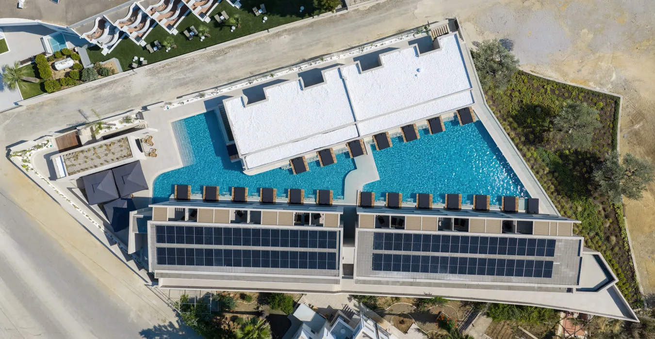 Top-down aerial of the new Dore Hotel building with its long pool and rooftop solar panels