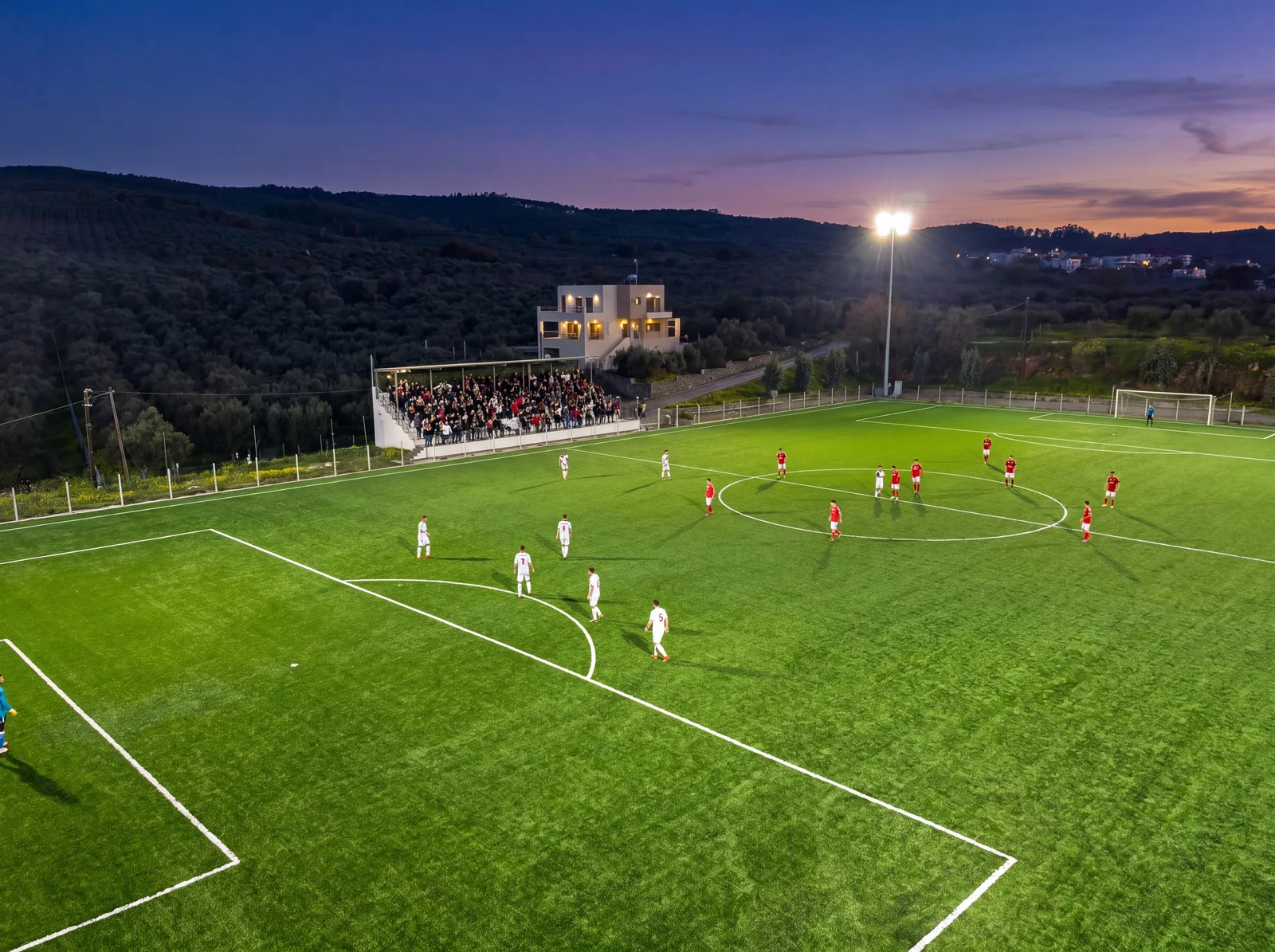 The clubhouse and packed grandstand of the Voukolies ground during an evening match