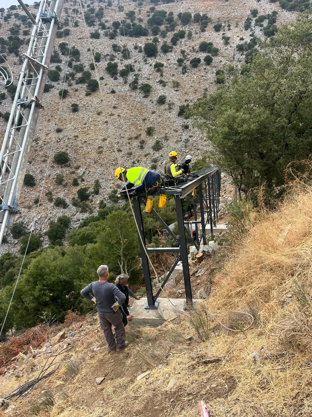 Crew working on the steel platform beside the cableway mast on the slope above the cave