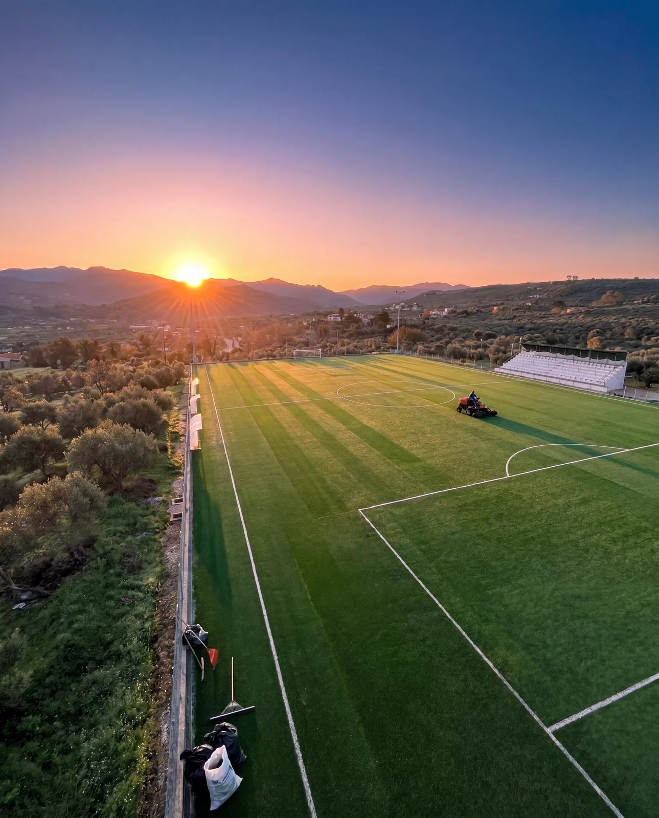 Grooming the synthetic turf of the Voukolies pitch at sunrise