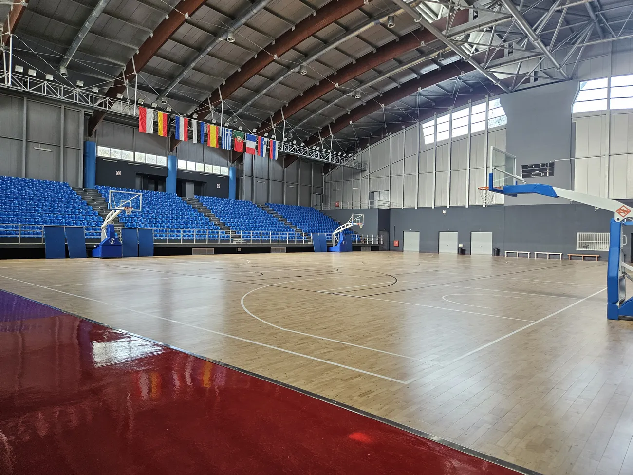 Court-level view of the Markos Karanastasis basketball hall with hoops and stands