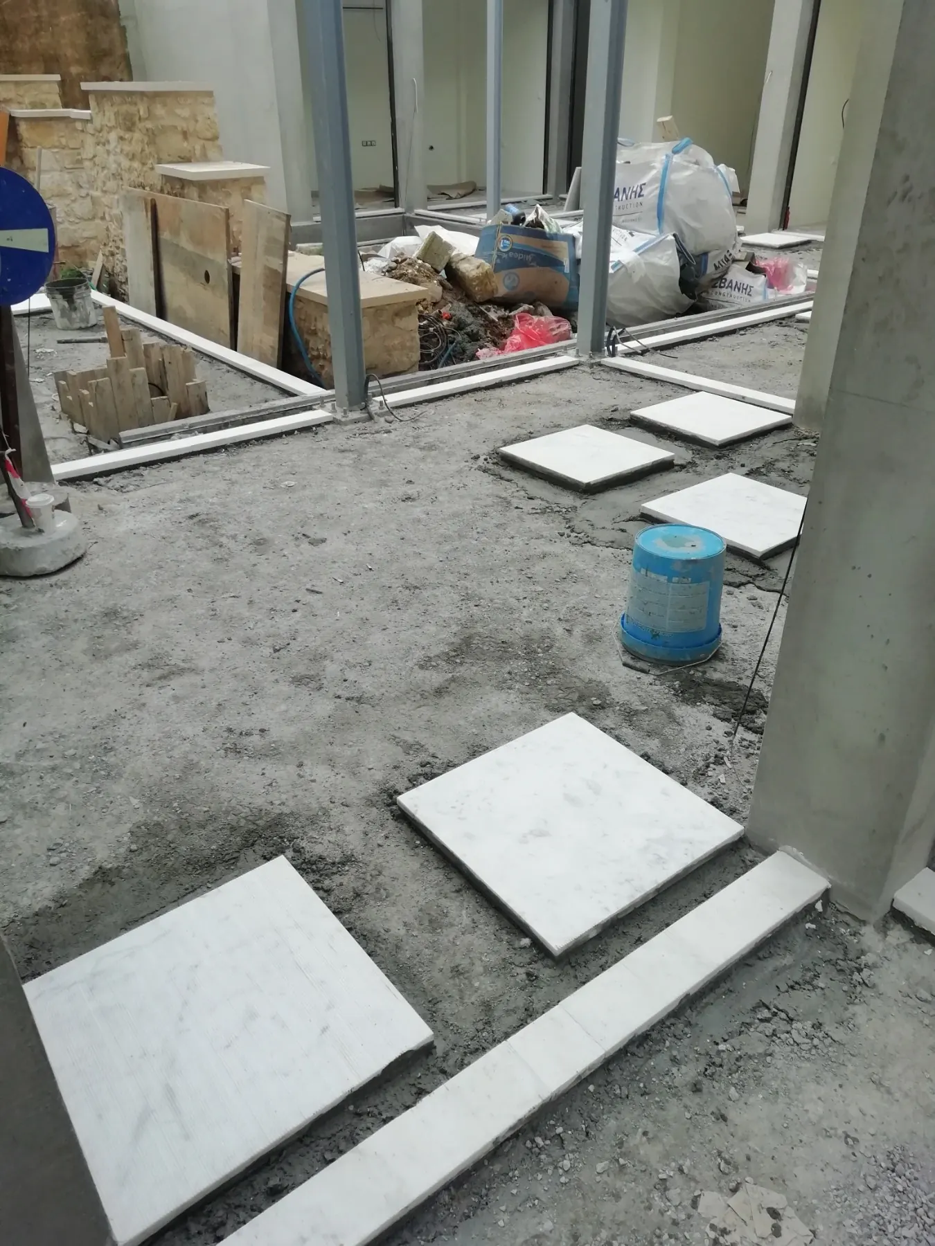 Marble paving slabs set out across the courtyard in January 2022, shopfronts glazed behind and the old stone wall preserved at the side