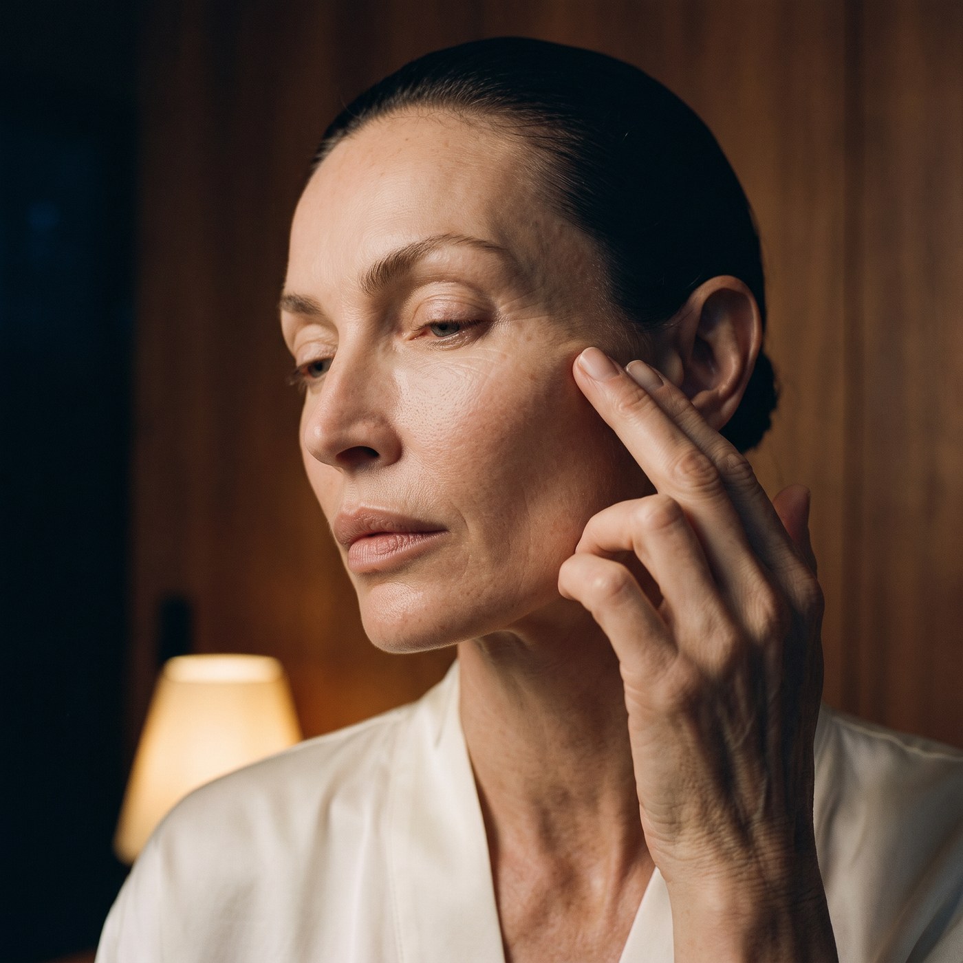 Close detail of a stroke of cream left unblended on the cheekbone under lamp light