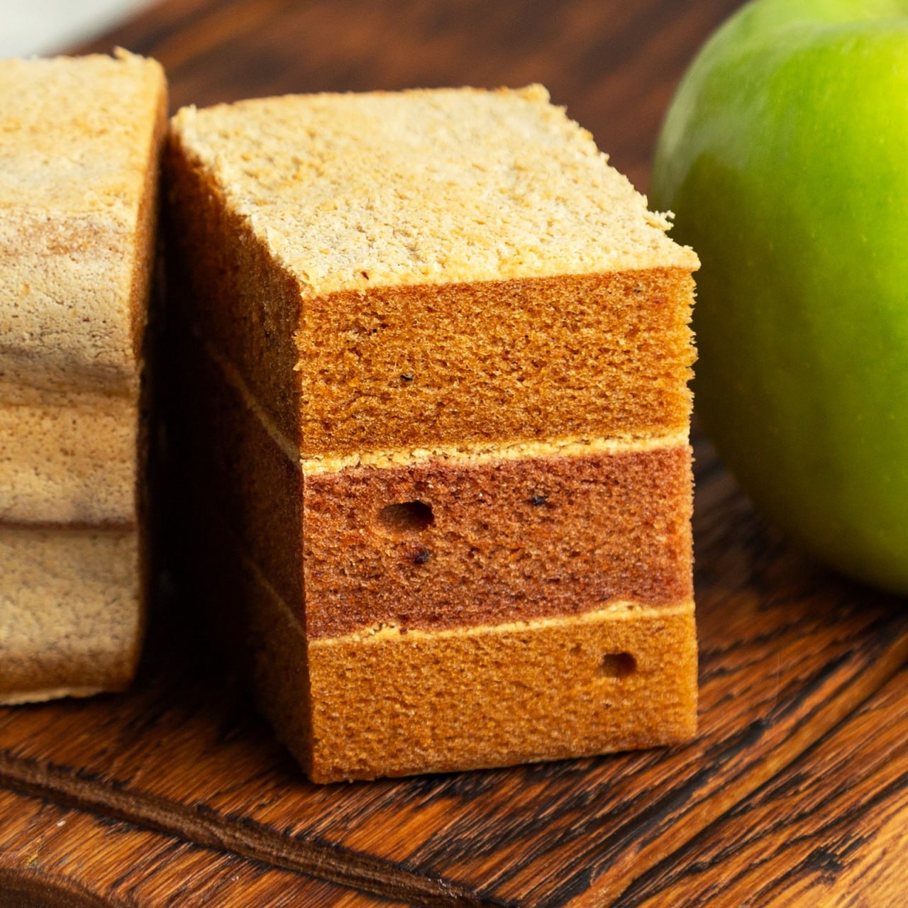 A tall block of layered apple pastila on a wooden board with a green apple