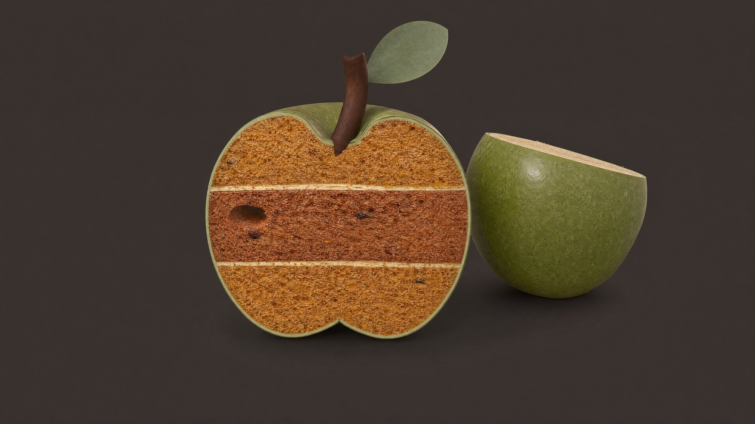 A pastila apple split open beside half a fresh green apple, showing the golden layered inside