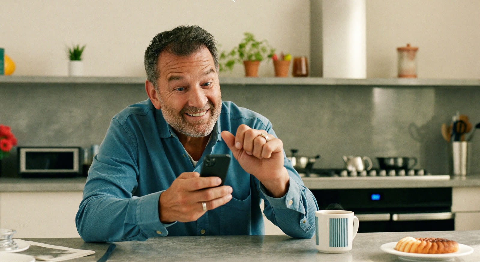 A man checking a reminder notification on his phone in his kitchen