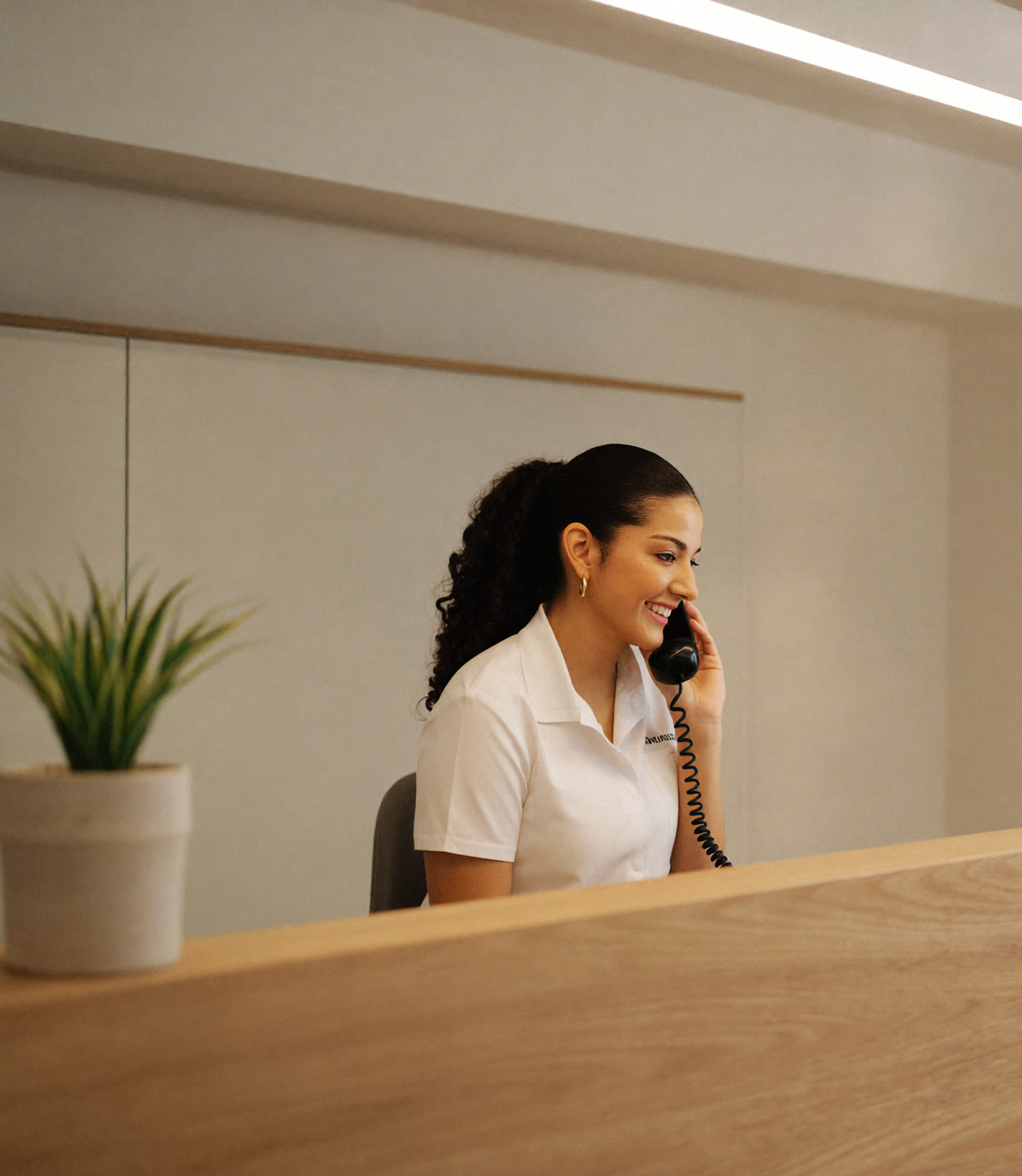 Front desk coordinator answering the phone with a smile