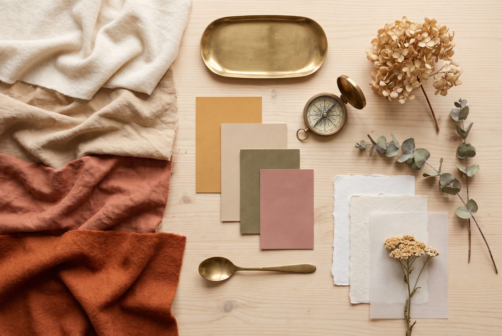 Moodboard-Anordnung aus Stoffmustern, Farbkarten und Objekten