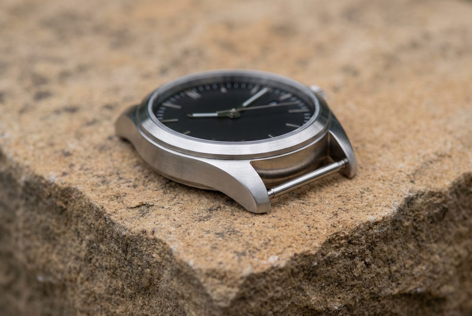 Armbanduhr mit gebürstetem Stahlgehäuse auf Sandstein