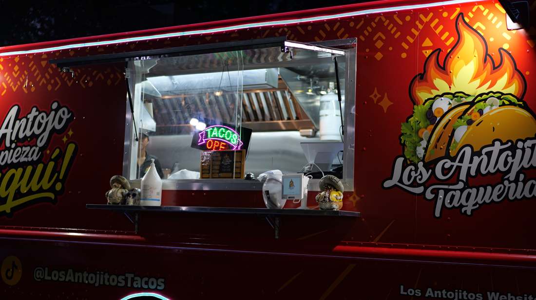 The serving window of the Los Antojitos truck lit up at night