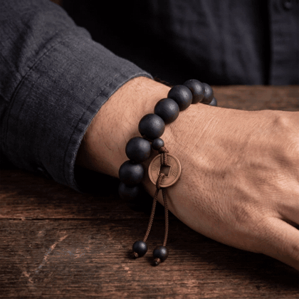 The Buddha Mala Bracelet worn on the wrist, the lucky coin swaying gently