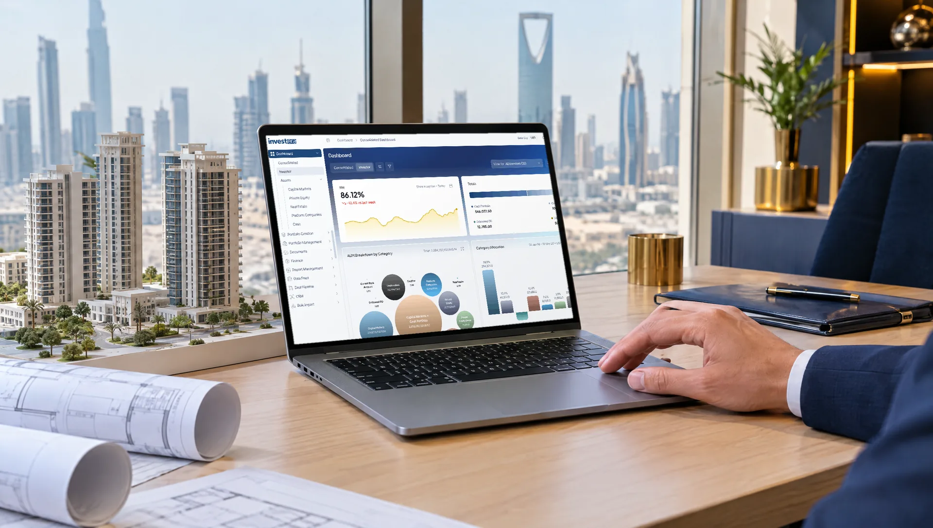Real estate investment desk with an architectural model and the Investera Pro consolidated dashboard on a laptop