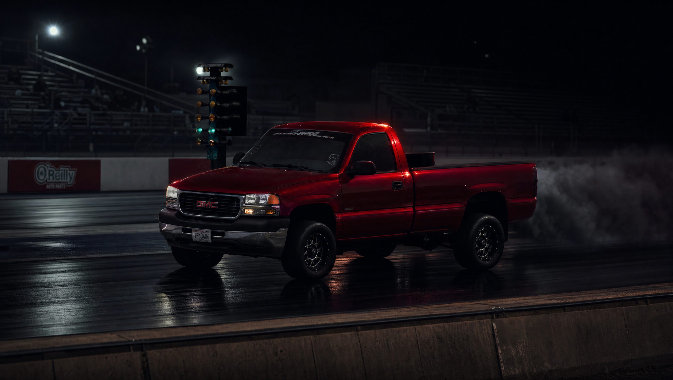 Red GMC Duramax launching at the drag strip at night