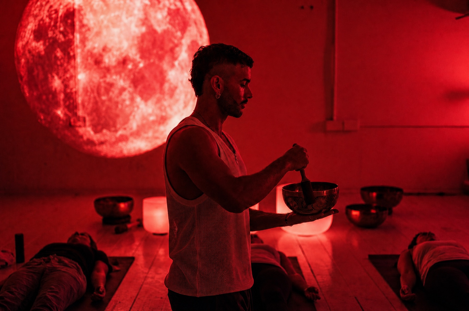 The Sound of Soma studio during a full moon sound bath, singing bowls glowing and guests lying down