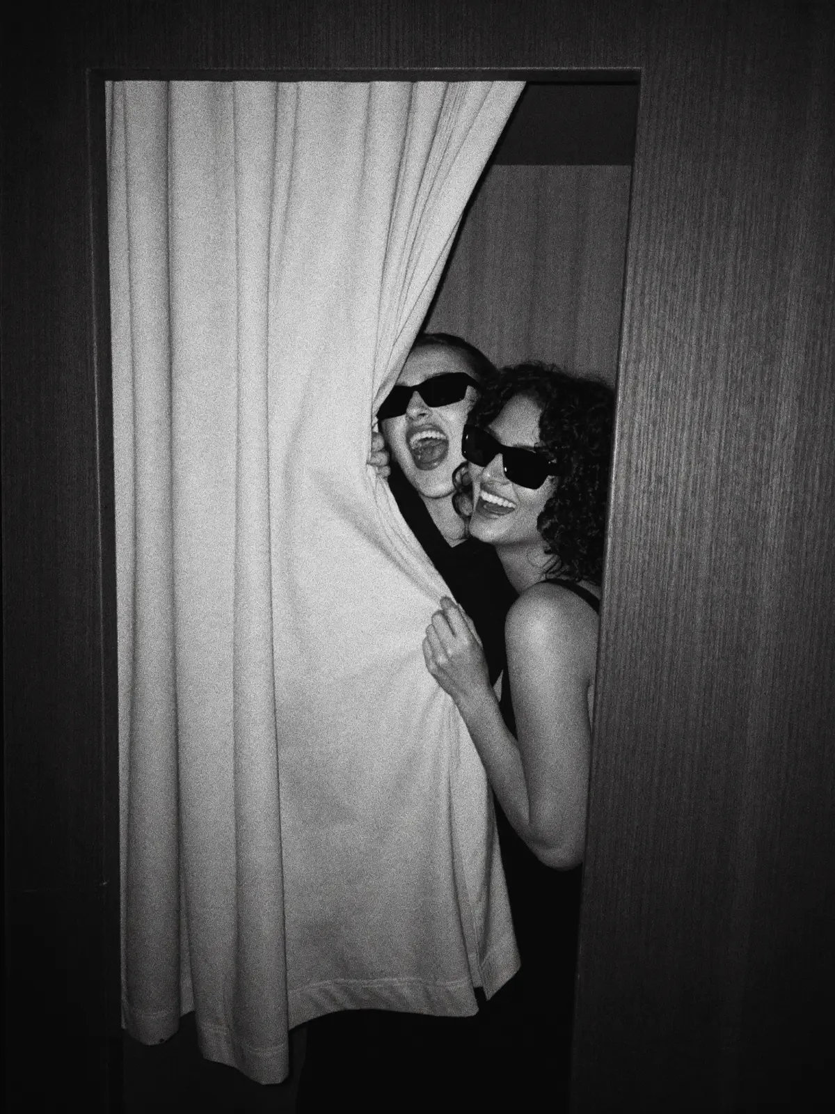 Two guests in sunglasses laughing behind The Revival's curtain