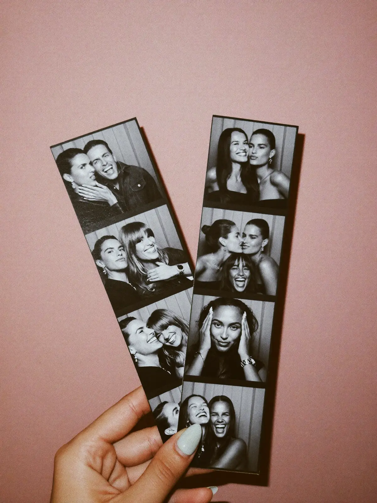 A hand holding two freshly printed black and white photo strips