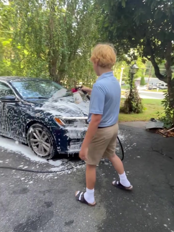 Michael spraying the hood of a sedan, close up