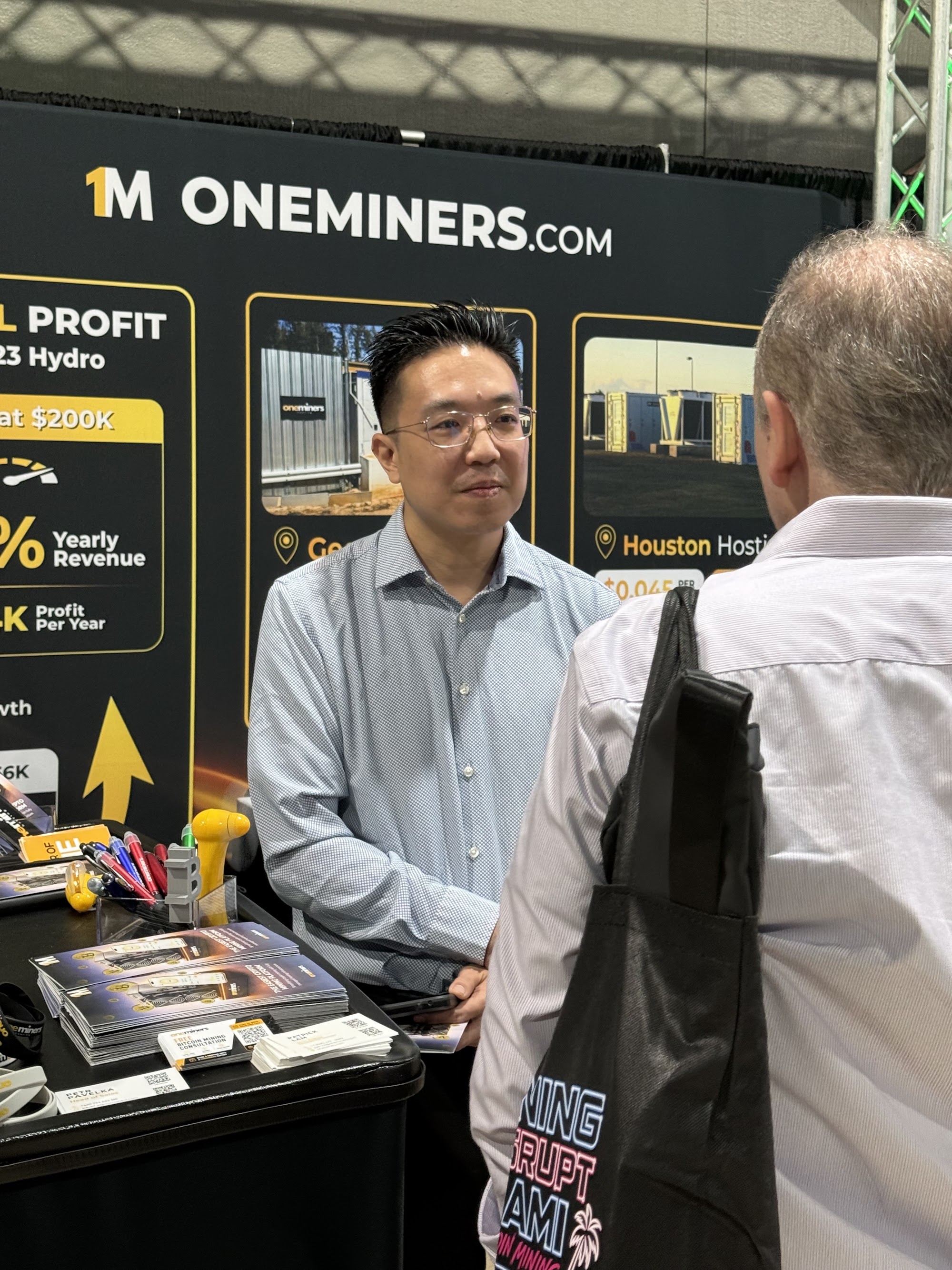 Visitors talking with the OneMiners team at the OneMiners booth at Mining Disrupt 2026
