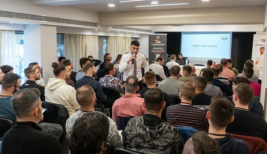 Ζωντανή εκδήλωση του Men of Style: γεμάτη αίθουσα με άντρες και ομιλητή στο μικρόφωνο