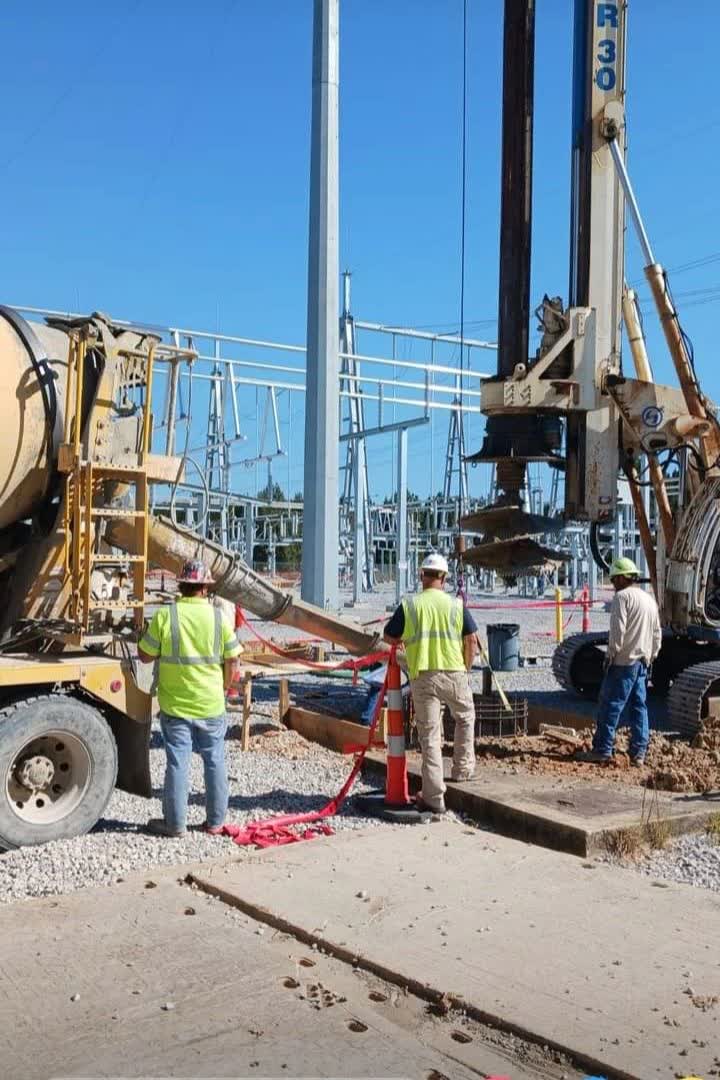 Crew placing concrete at a substation with the drill rig on site