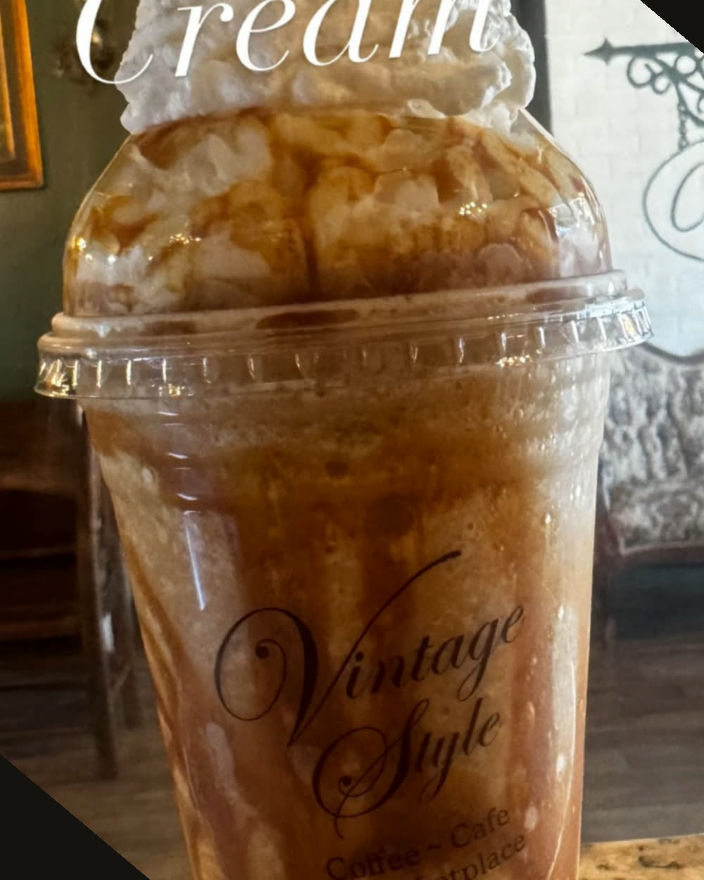 A caramel cream cold drink topped with whipped cream in a branded Vintage Style cup