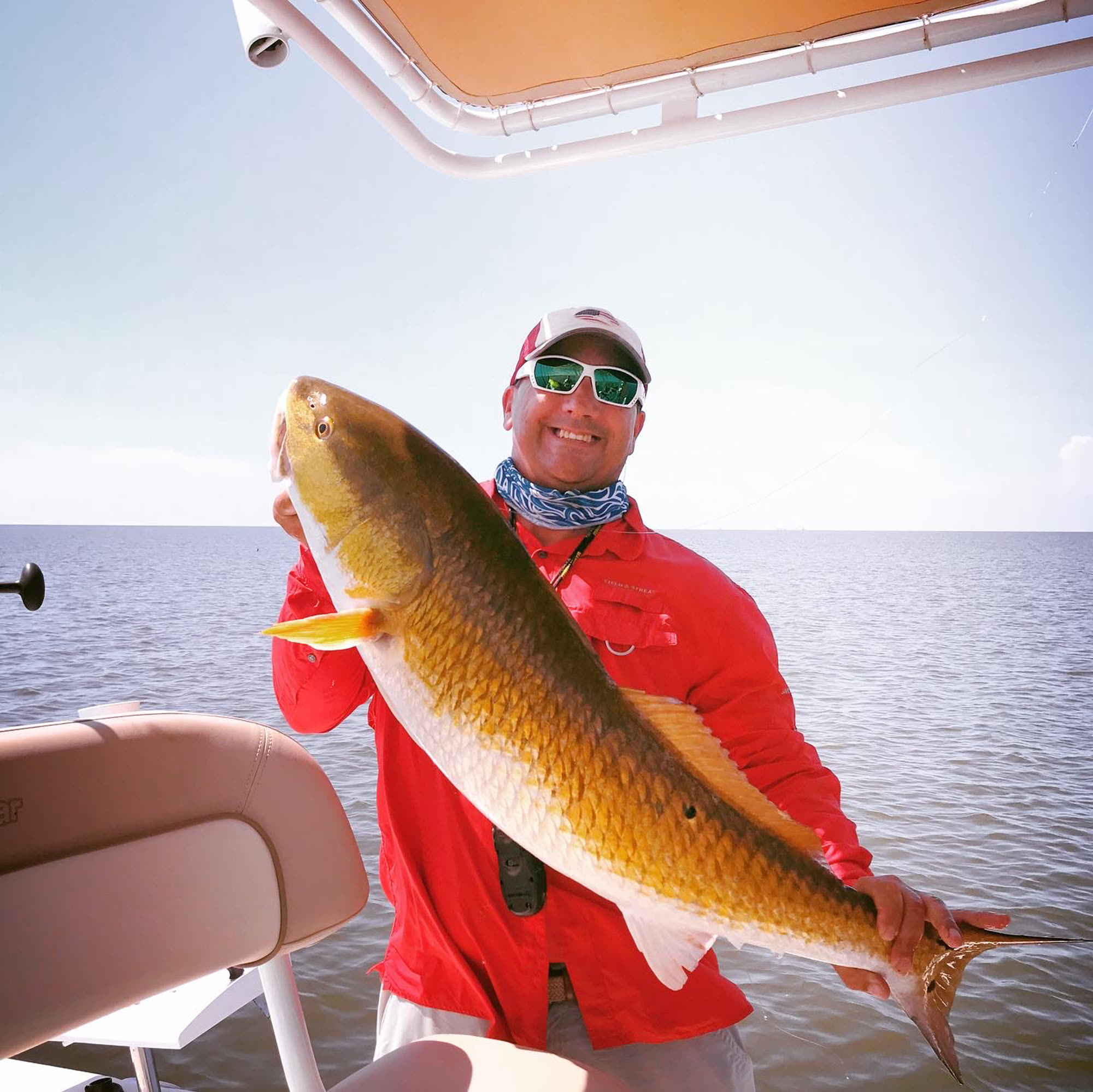 An angler holding a bull redfish aboard the Difference Maker