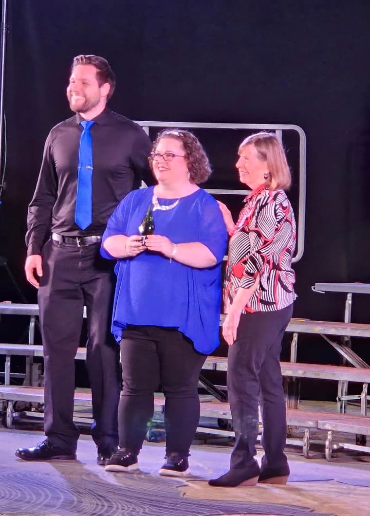 The director and two members on stage with the Sparkle Award