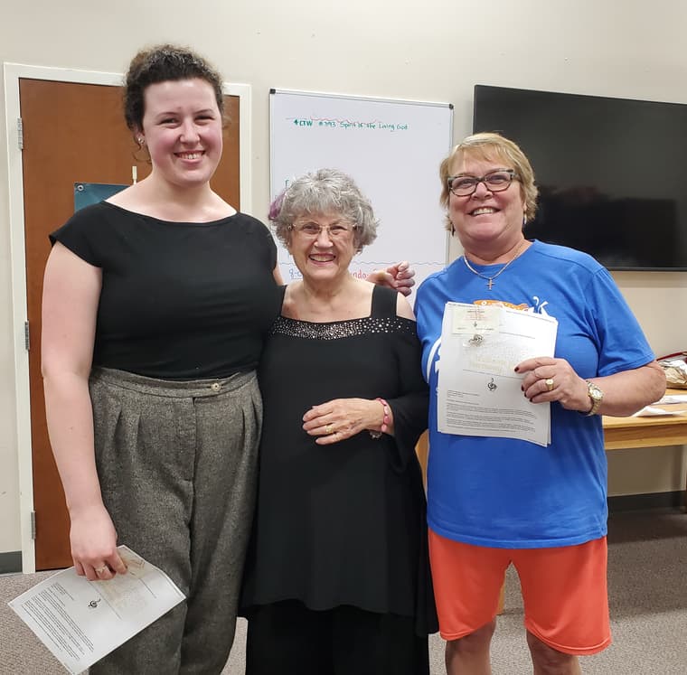 Three members standing together welcoming new singers