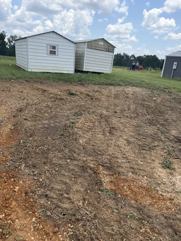 The same yard beside the storage building with the stump and brush gone and the ground graded smooth