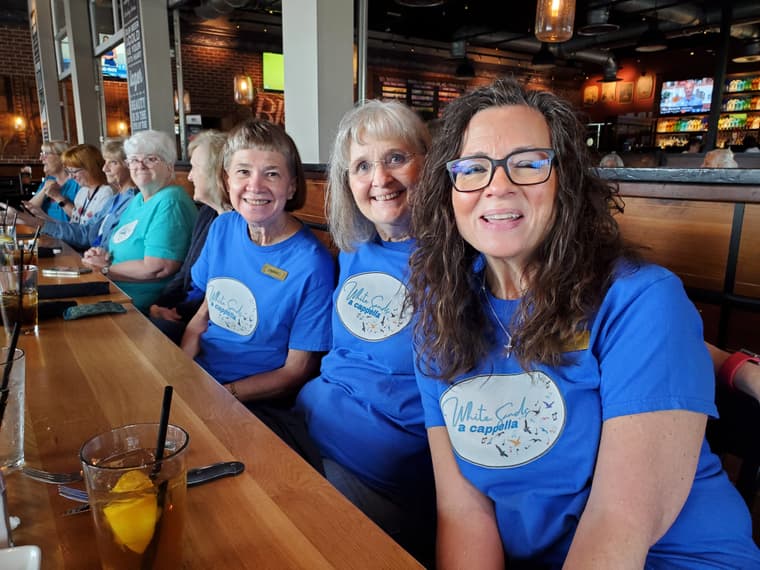 Members in matching blue shirts at a long lunch table