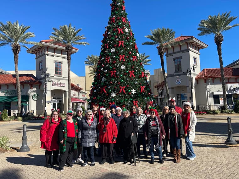 The chorus outdoors by a tall Christmas tree