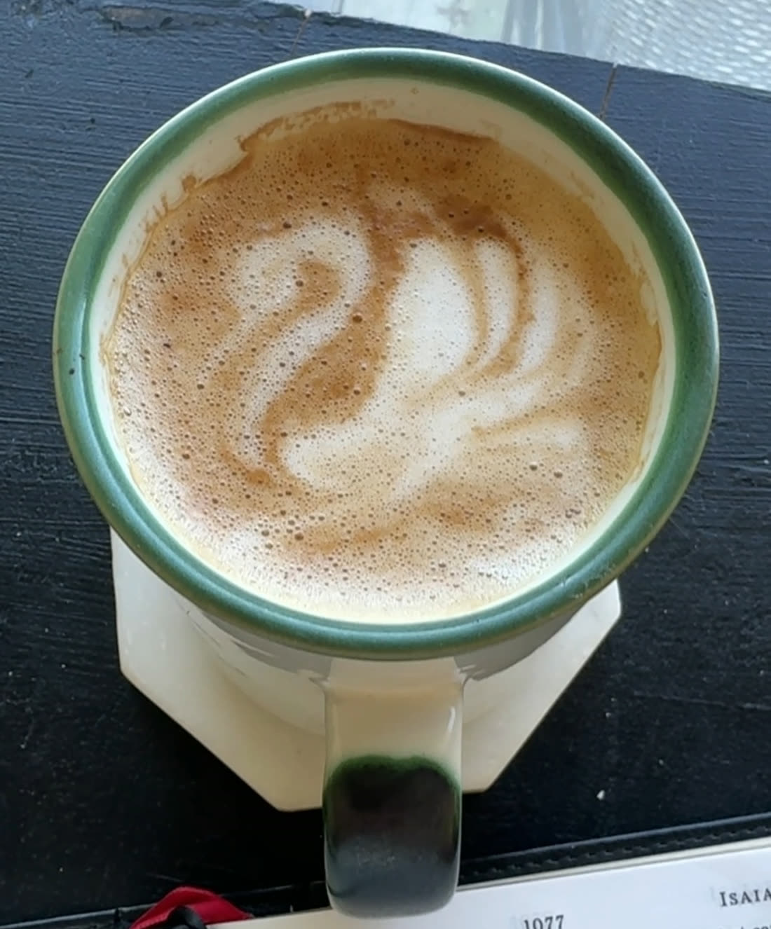 A latte poured with rosetta art in a green-rimmed ceramic mug