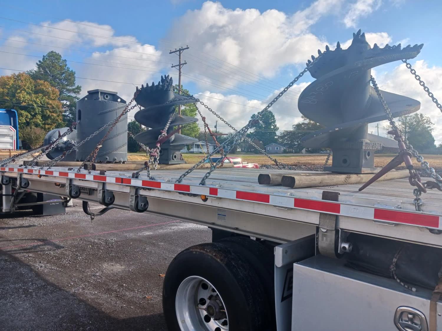 Large diameter augers and drilling tools loaded on a flatbed trailer