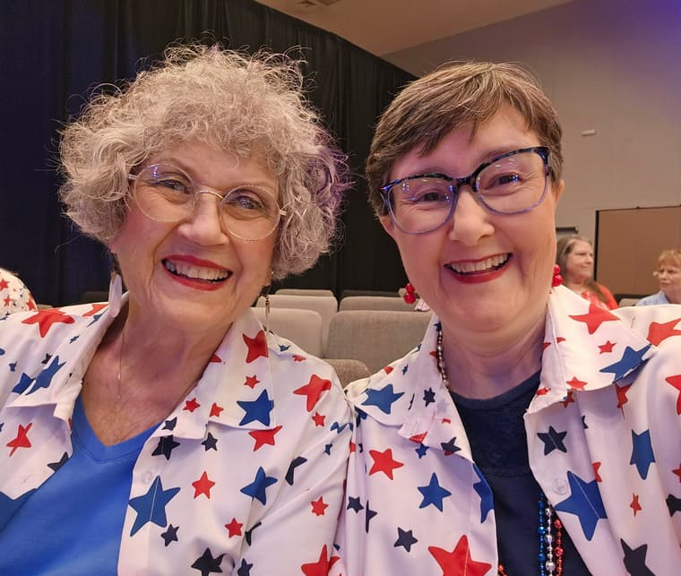 Two chorus members laughing together in matching shirts