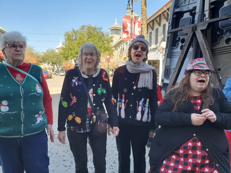 Four members singing outdoors in holiday clothes