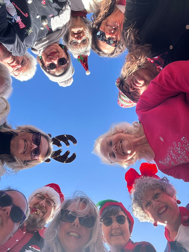 Members in a circle photographed from below against a blue sky