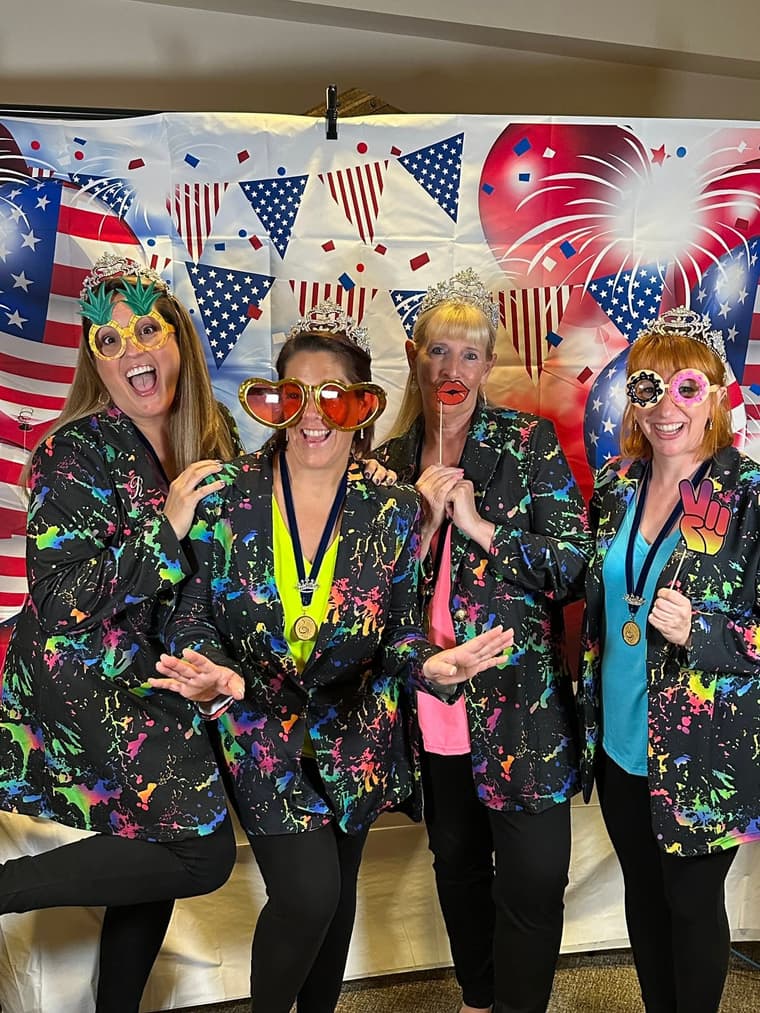 Three members posing in sunglasses at a patriotic photo booth