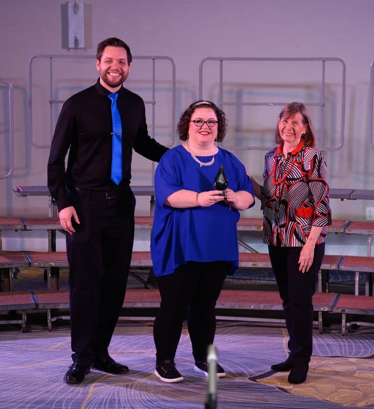 Three members accepting the Sparkle Award on stage
