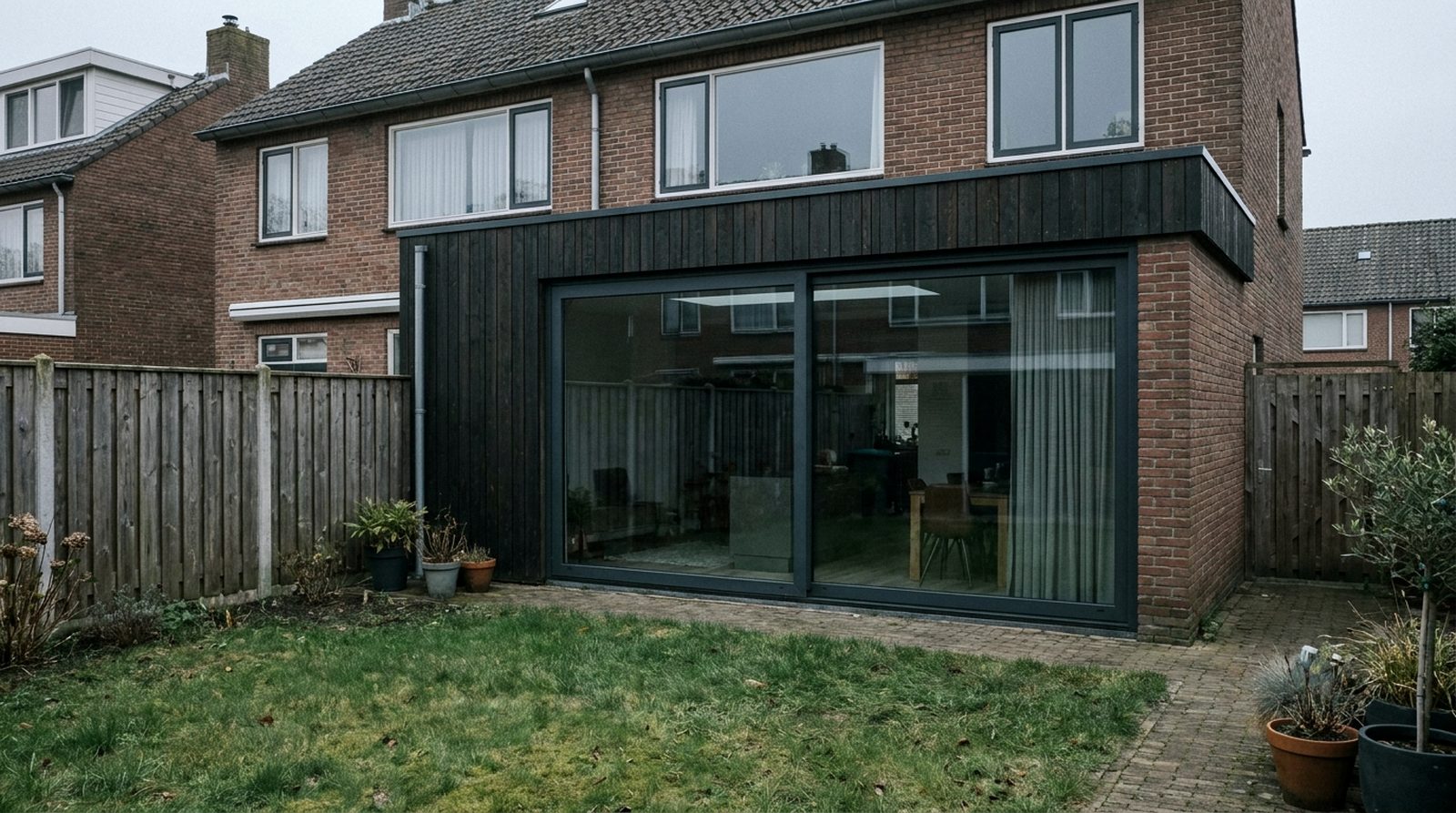 Moderne platdak-aanbouw met schuifpui aan de achterzijde van een Nederlandse jaren-30 woning