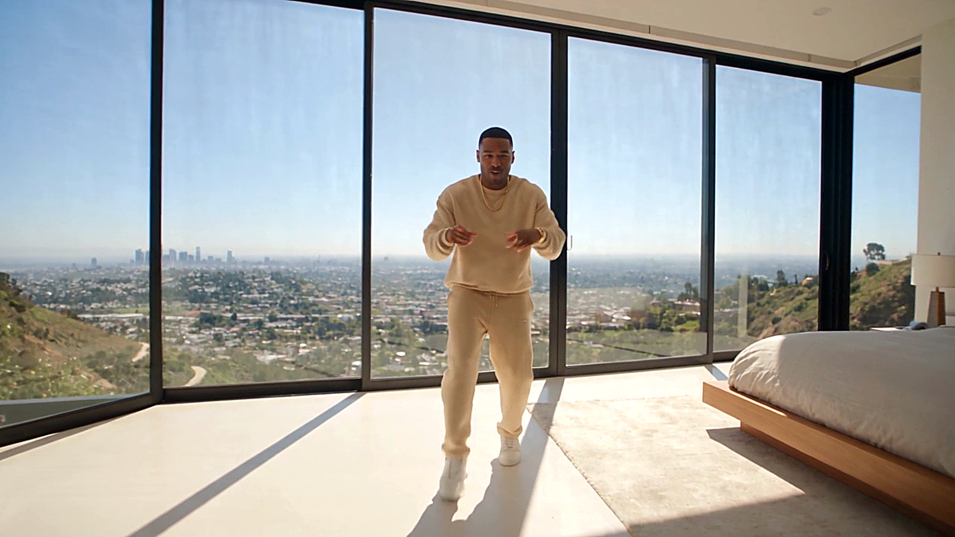 Dancer moving through a glass-walled Hollywood Hills mansion above the Los Angeles skyline
